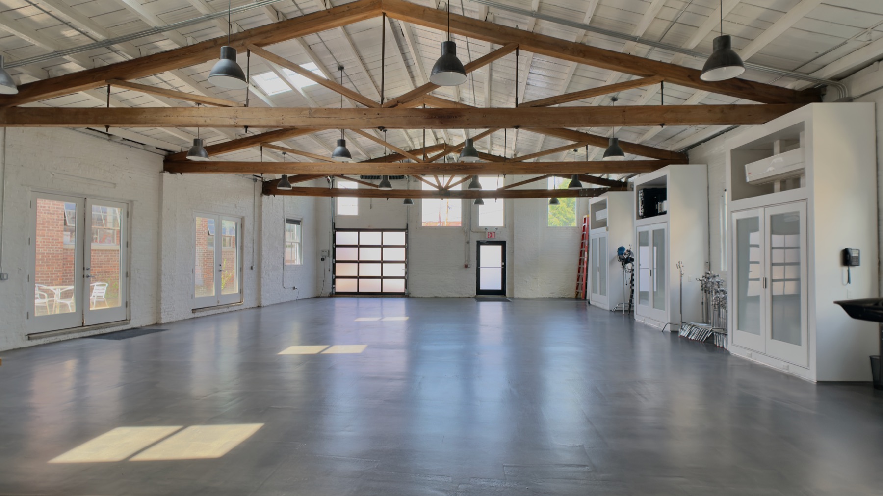 Open studio loft with timber trusses, skylights and a glass-panel garage door